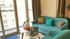 Ein modernes Wohnzimmer mit einem türkisfarbenen Sofa, einem kleinen Couchtisch und einem Blumentopf.