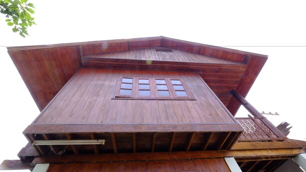 Un edificio de madera de varios niveles, con techo inclinado y una ventana central.