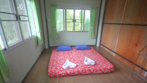Una habitación con cama, dos almohadas y ventana con cortinas.