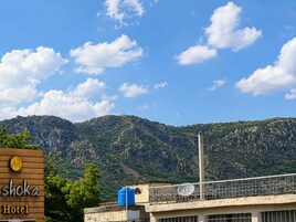 Señal de hotel con la leyenda 'shoka Hotel', sobre un fondo de montañas y cielo despejado.