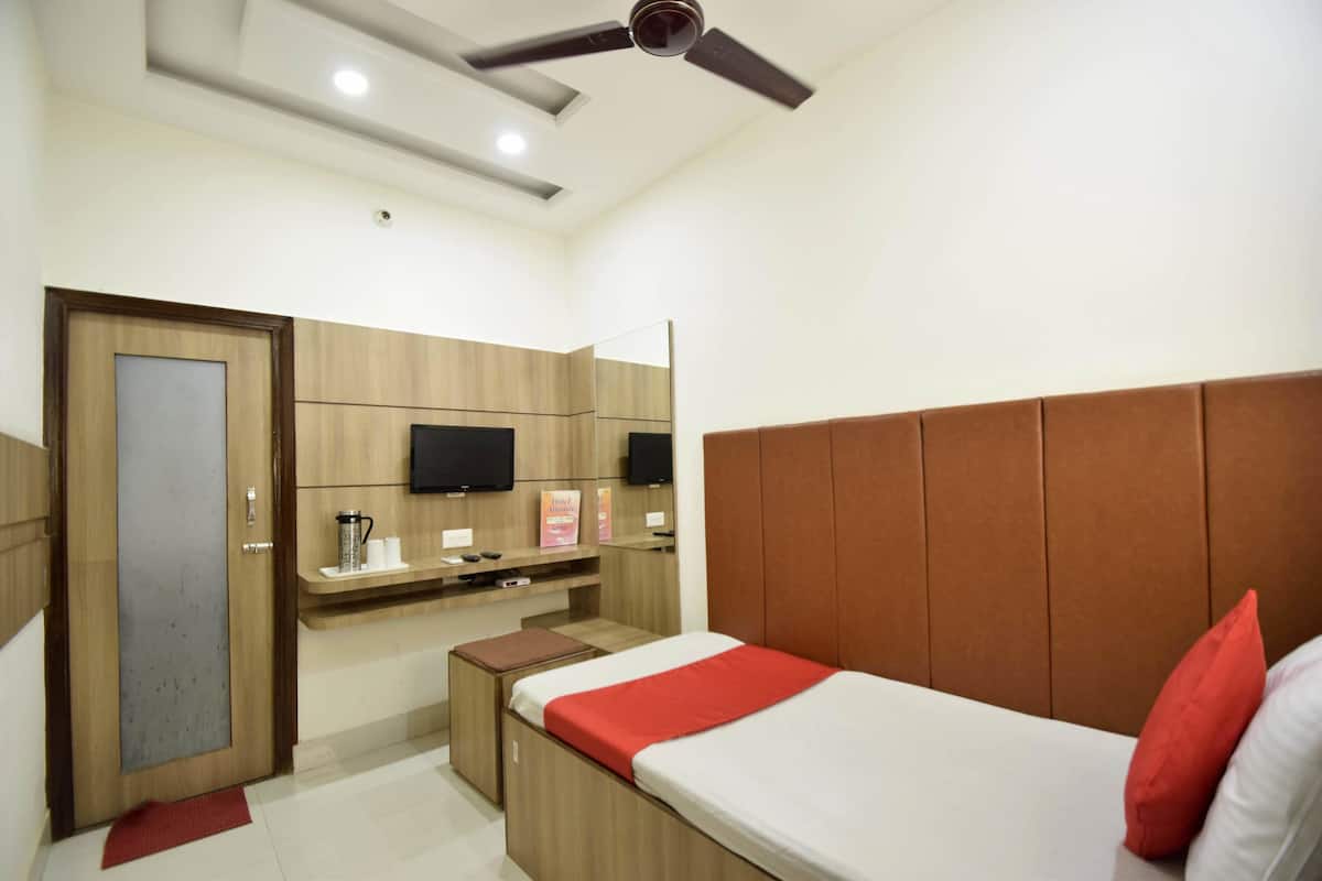 A hotel room with a bed, a desk, a mirror, a television, and a ceiling fan.