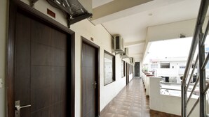 Un pasillo con puertas, unidades de aire acondicionado y vistas a un bar y edificios.
