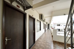 A corridor with doors, air conditioning units, and a view of a bar and buildings outside.