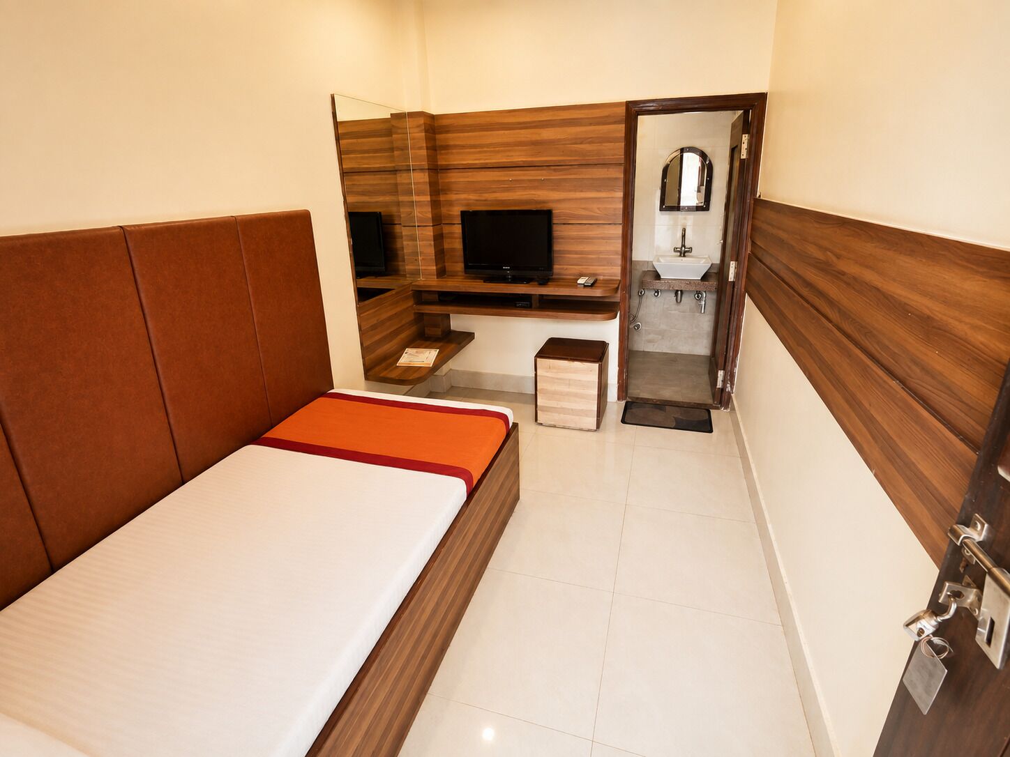 Une chambre d’hôtel avec un lit, une télévision, un petit bureau et une salle de bain.