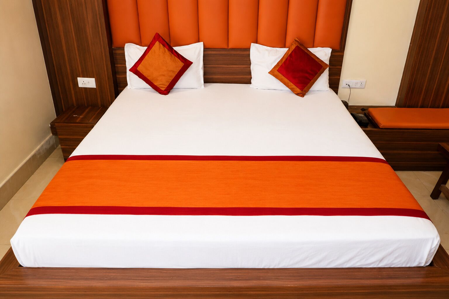 Una habitación de hotel con una cama grande, cabecera de madera y dos mesitas de noche.