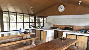 Une cuisine spacieuse avec des bancs en bois, une grande fenêtre et une horloge au mur.