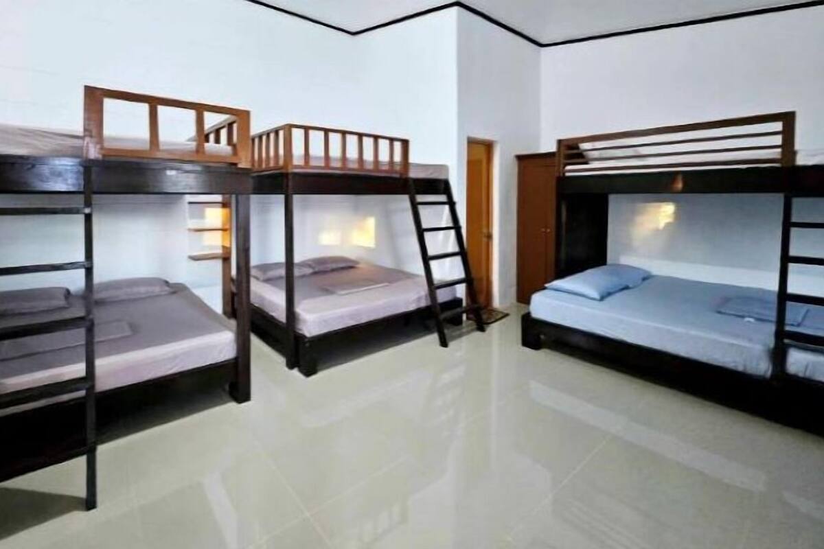 Three bunk beds in a room with white walls and a tiled floor.