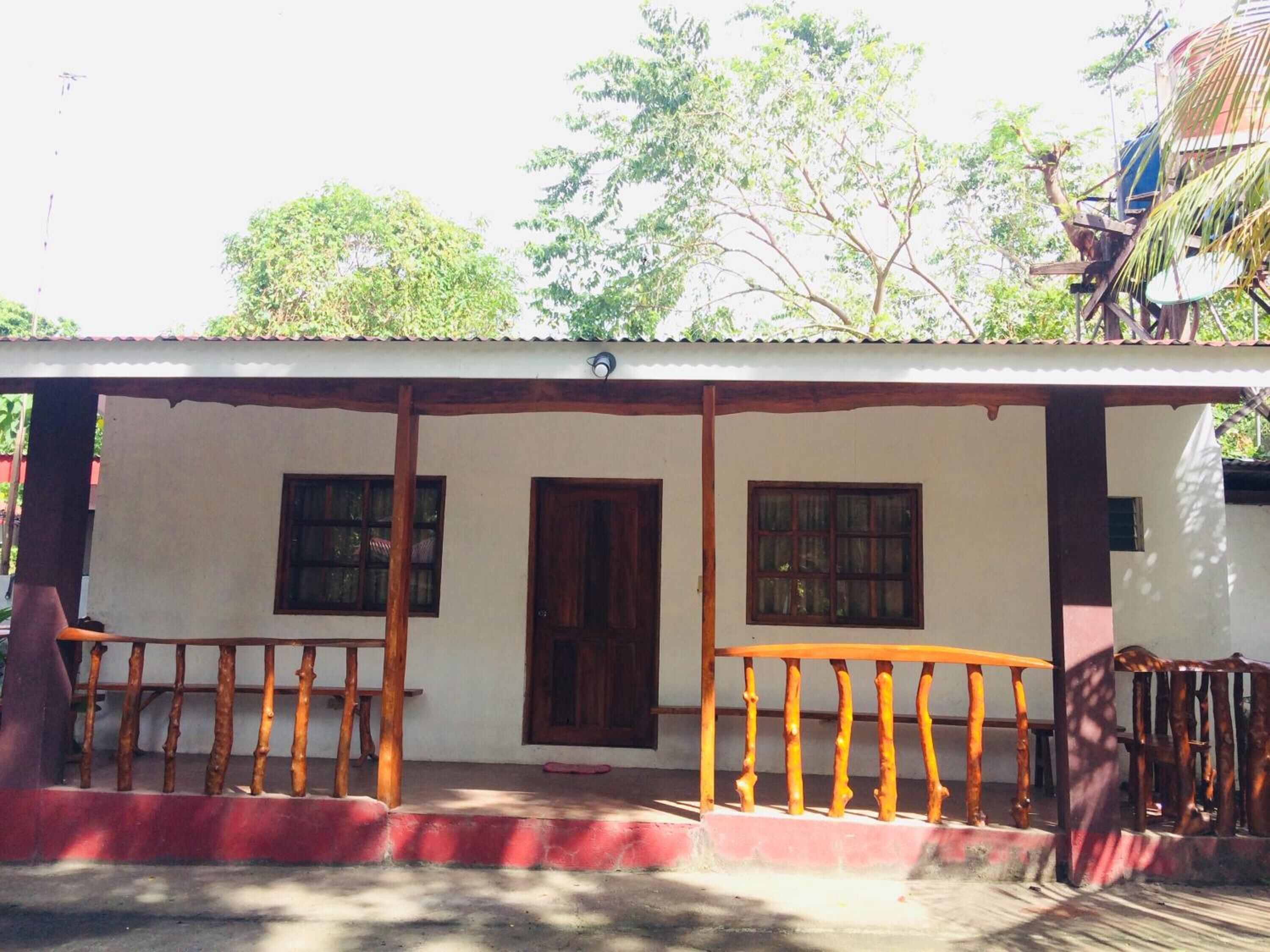 A single-story building with a porch, two windows, and a door.