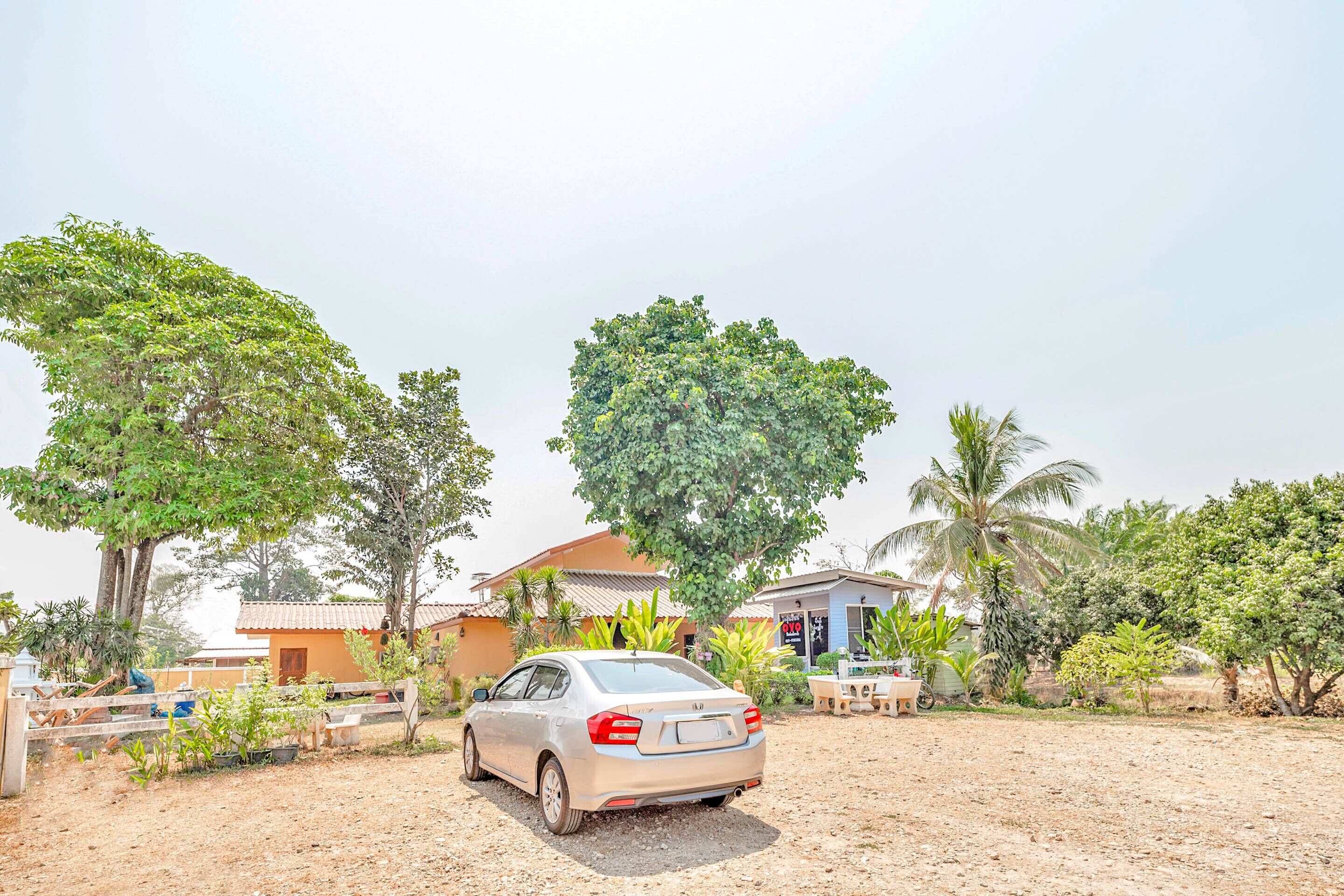 A car parked in a driveway with a house and palm trees in the background.