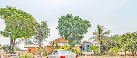 A car parked in a driveway with a house and palm trees in the background.