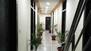 Un pasillo con plantas en macetas, una escalera y una puerta al final.