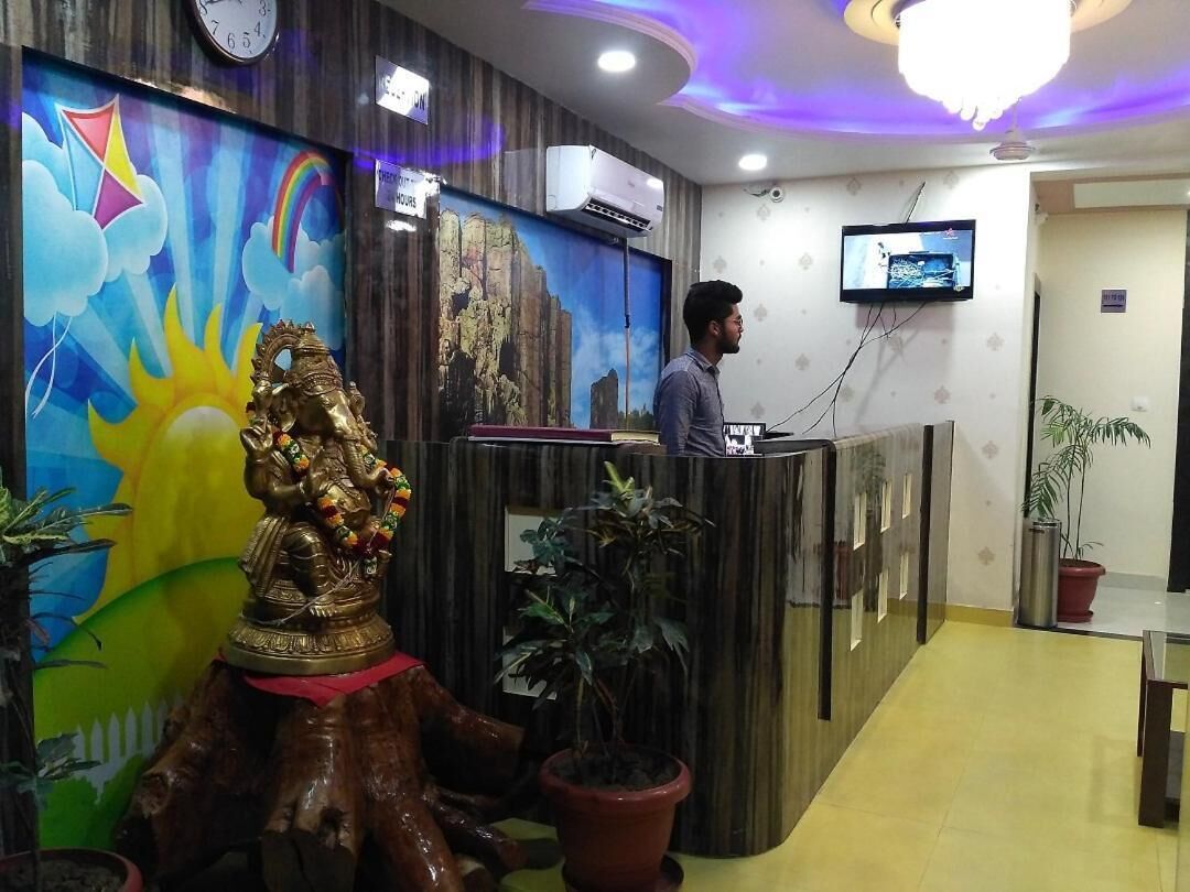 Un área de recepción con un mostrador de madera, un reloj de pared, un televisor y plantas en macetas.