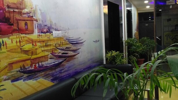Un vestíbulo con un mural de una escena fluvial, un sofá negro y plantas en macetas.