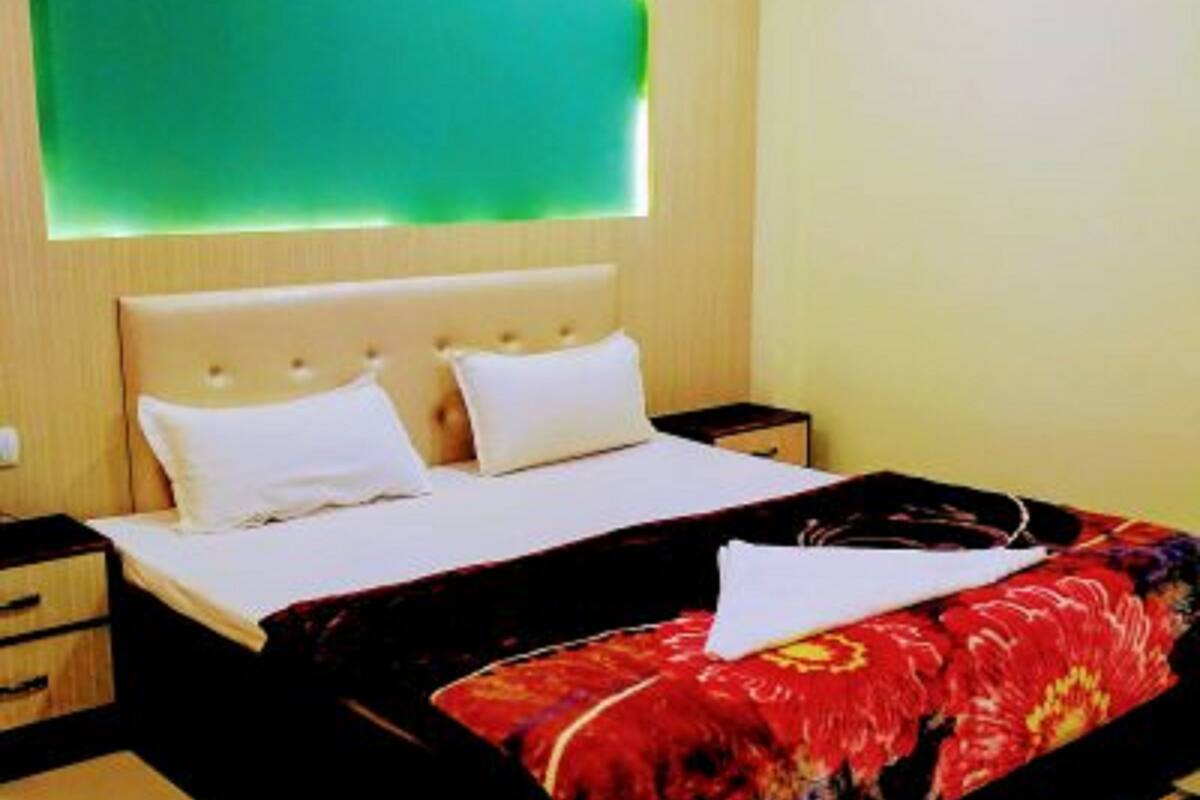 A hotel room with a bed, a nightstand, and a wall-mounted light fixture.