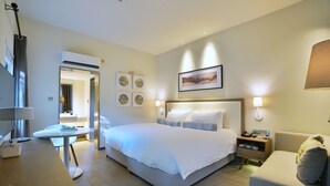 A modern hotel room with a large bed, bedside tables, a desk, and a chair.