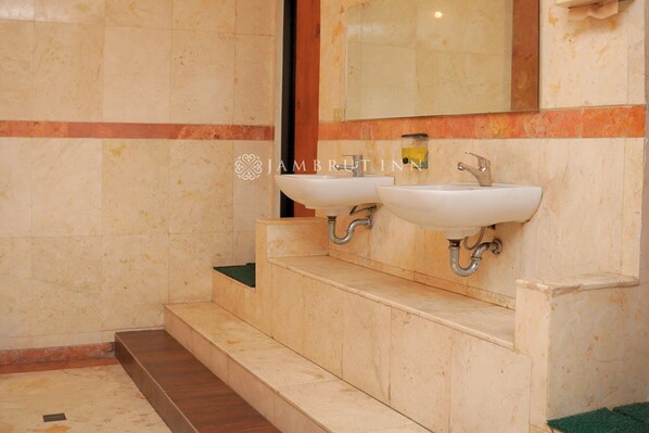 Une salle de bain avec deux lavabos, un miroir et un sol carrelé.