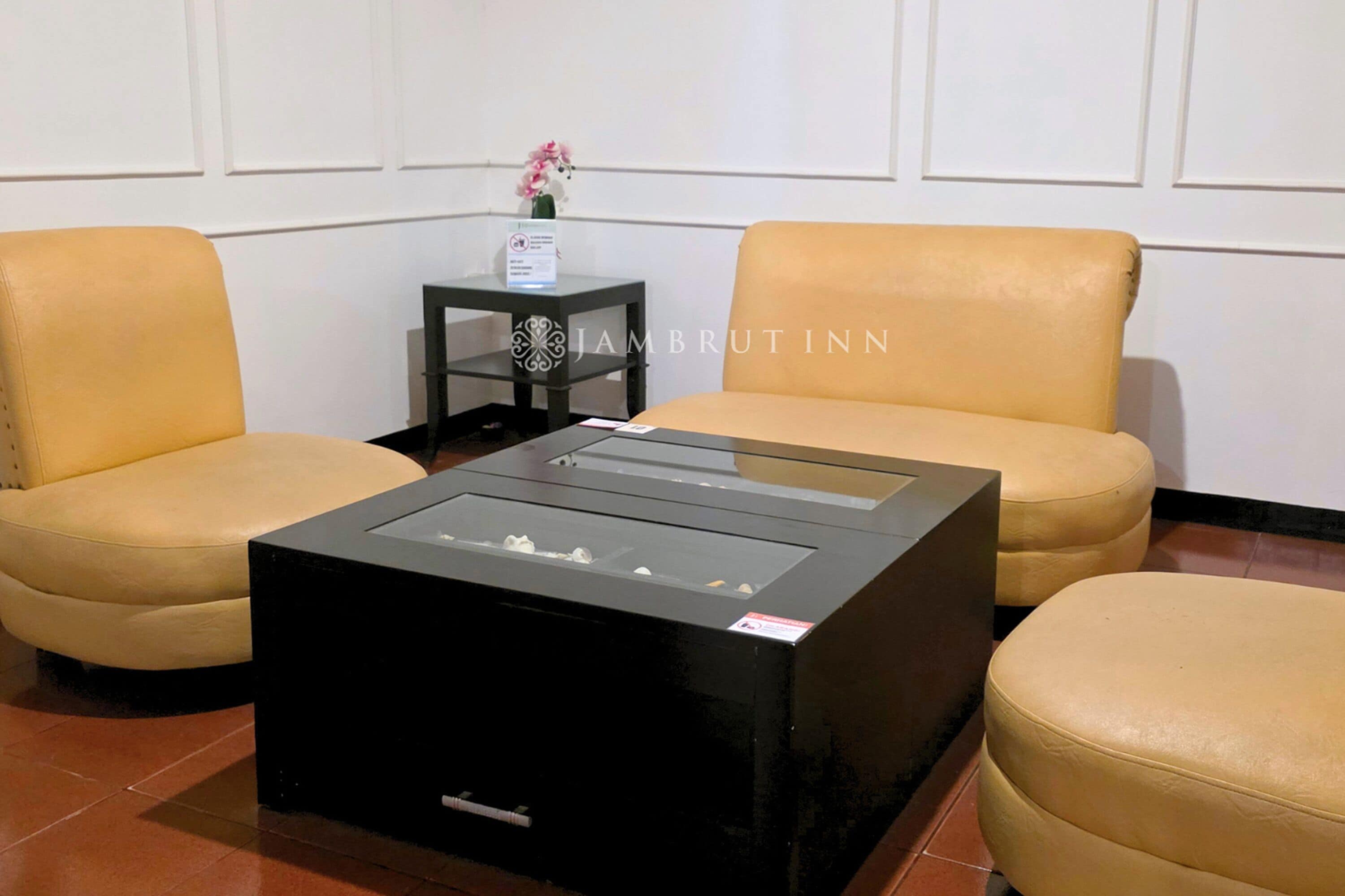 A room with two yellow leather sofas, a black coffee table, and a small table with a vase of flowers.