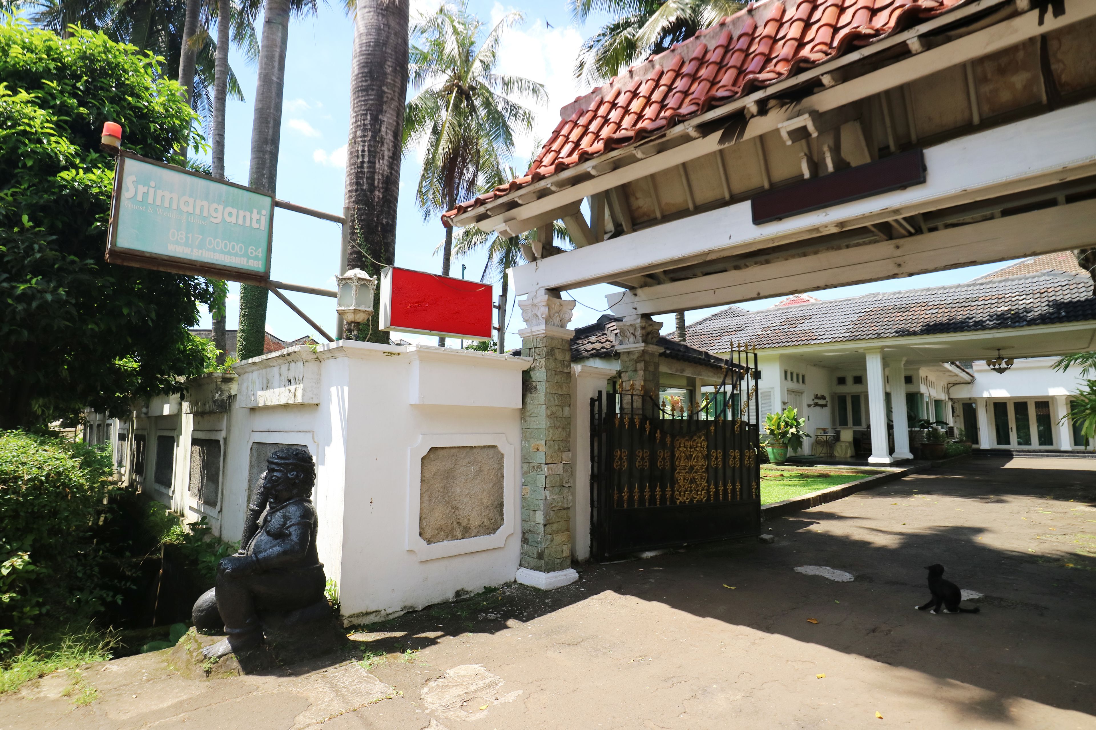 A building entrance with a sign, a statue, and a gate.