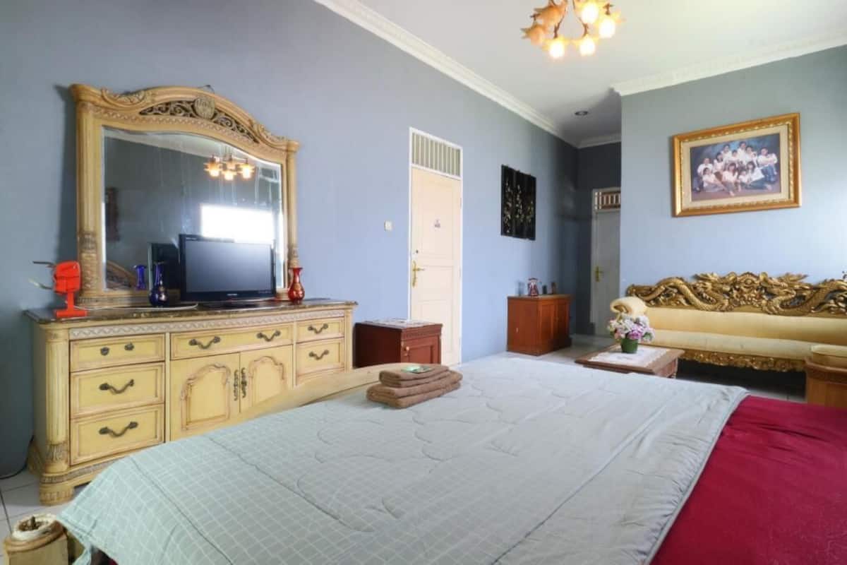 Ein Schlafzimmer mit einem großen Bett, einem Schminktisch, einem Fernseher, einem Sofa und einem Spiegel.