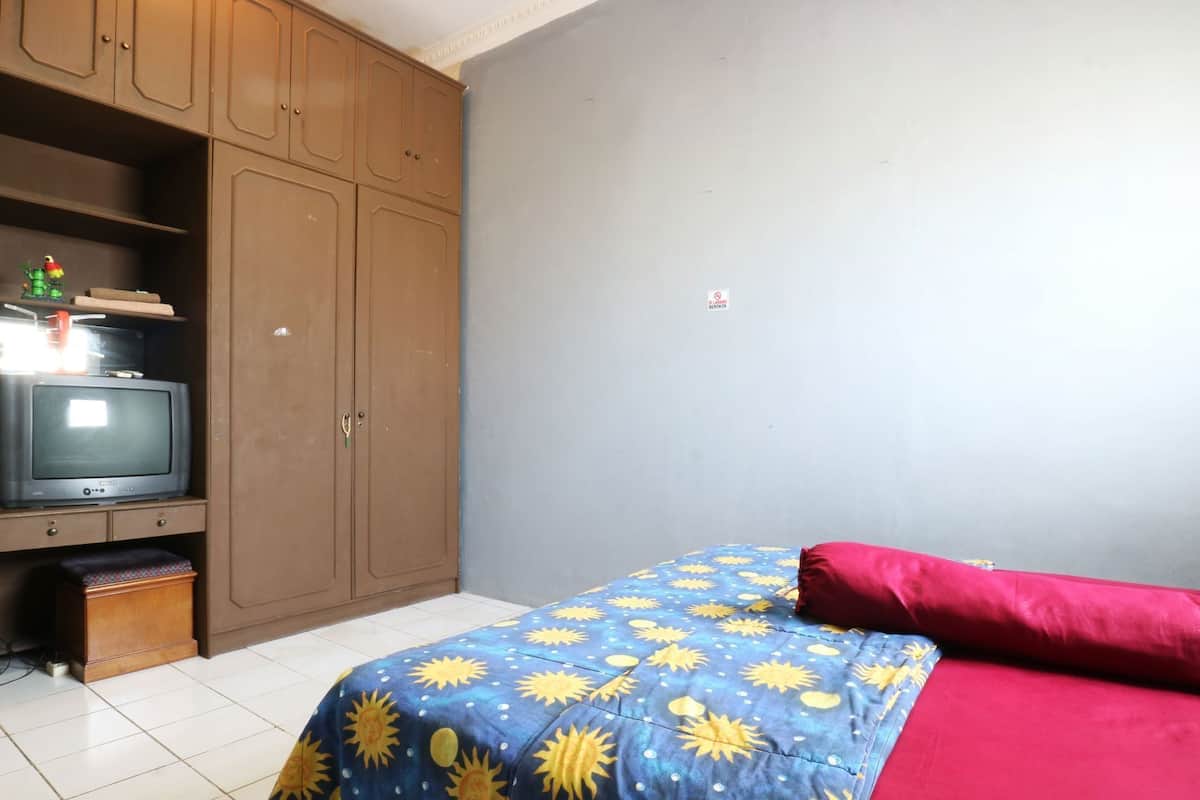 Ein Schlafzimmer mit einem Bett, einem Fernseher auf einem Regal und einem Kleiderschrank.