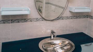 Une salle de bain avec un miroir rond, un lavabo et deux armoires.
