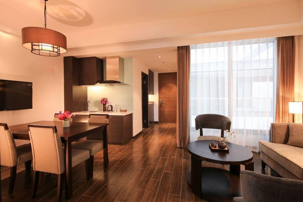 Una habitación de hotel moderna con zona de comedor, sofá y televisor.