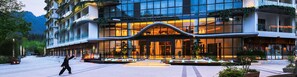 A modern hotel with a curved facade, large glass windows, and outdoor seating areas. - Sunforest Resort Hotel (Huangshan)