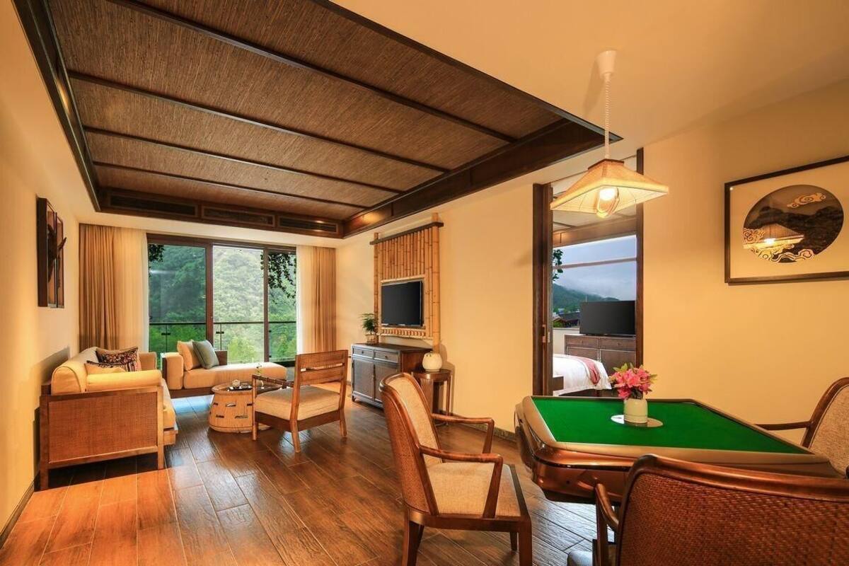 Amplia habitación con mesa de billar, asientos cómodos, televisor y un ventanal con vistas al exterior.