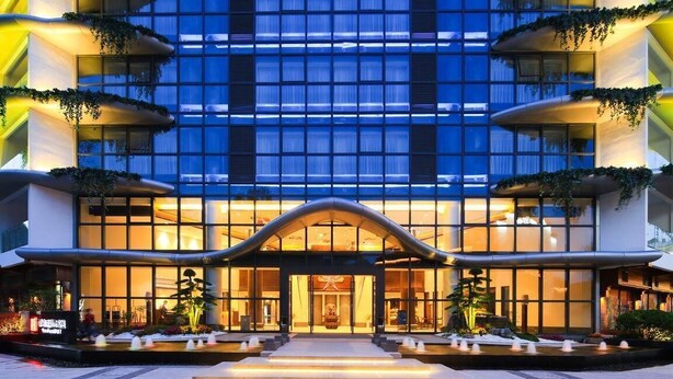 Un hotel moderno con una fachada simétrica, ventanas amplias y una entrada central con un porche curvo.