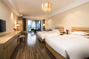 A hotel room with two beds, a desk with a flat-screen TV, a chair, and a large window offering a view of the outdoors. - Sunforest Resort Hotel (Huangshan)