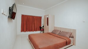 Une chambre à coucher avec un lit, un bureau, une chaise, un miroir et une fenêtre avec des rideaux.
