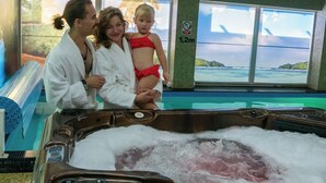 A hot tub with a view of the ocean, a window with a no smoking sign, and a reflection of palm trees. - Wydma Resort (Trzebiatow)