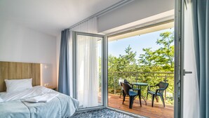 A hotel room with a bed, a small table, and a balcony with chairs. - Wydma Resort (Trzebiatow)