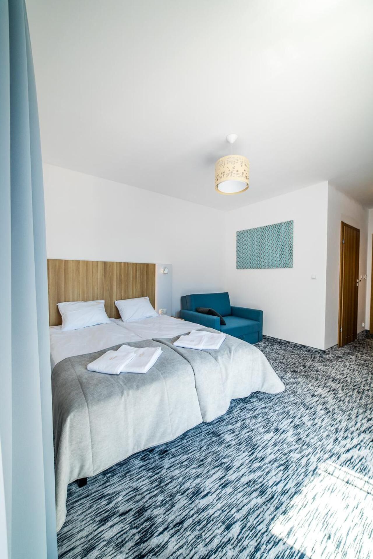 Une chambre d’hôtel avec un grand lit, un canapé bleu, une décoration murale à motifs et un sol recouvert de moquette.
