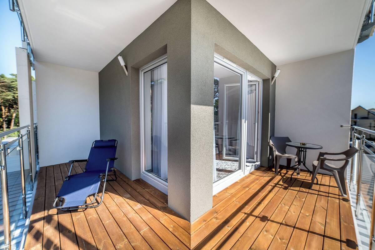 Uma varanda com piso de madeira, uma cadeira azul e uma mesa com cadeiras.