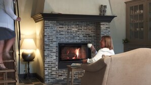 Un salon chaleureux avec une cheminée, un sol à carreaux et une échelle en bois.