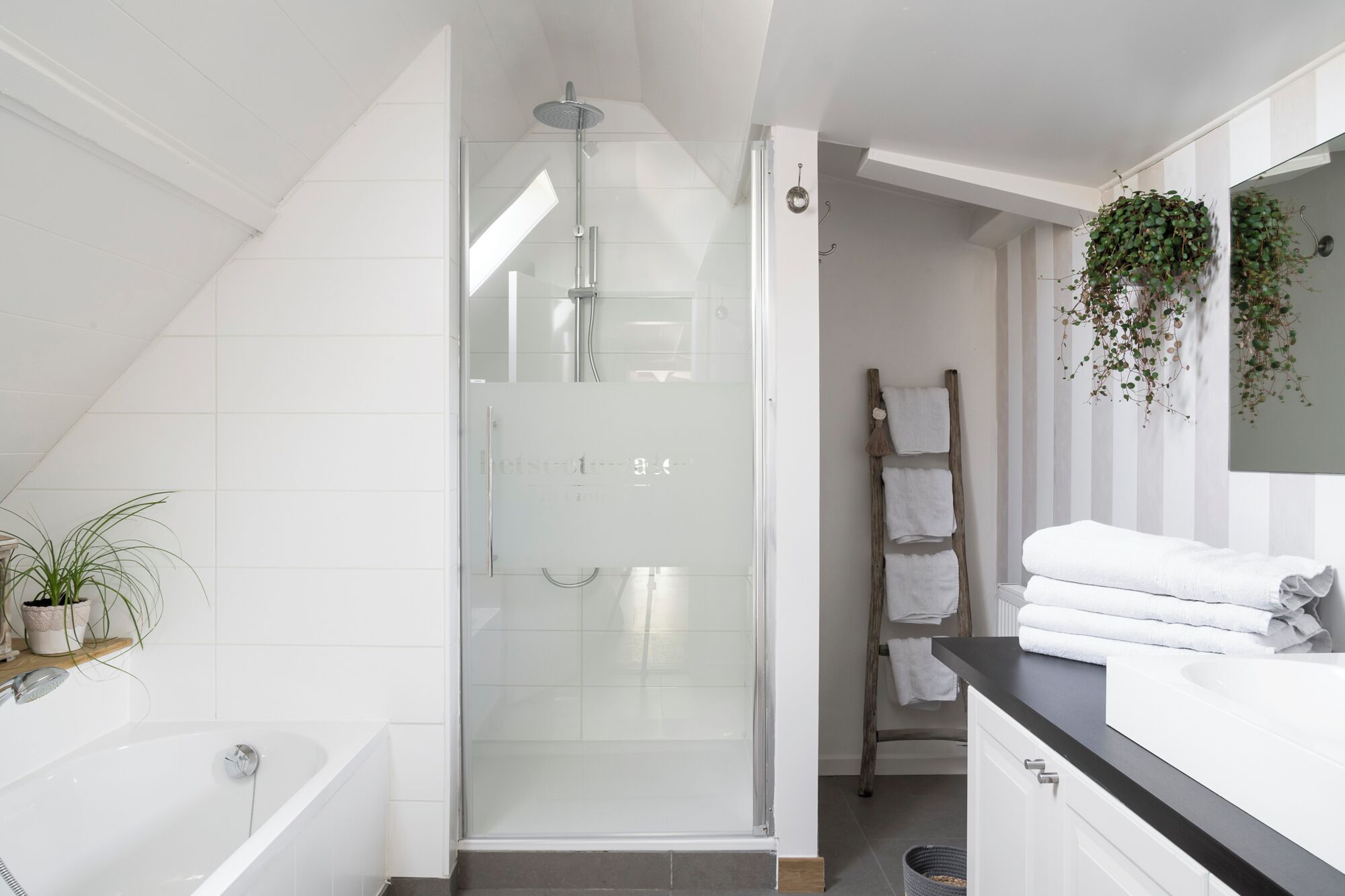 A modern bathroom with a glass-enclosed shower, a white bathtub, and a vanity with a mirror.
