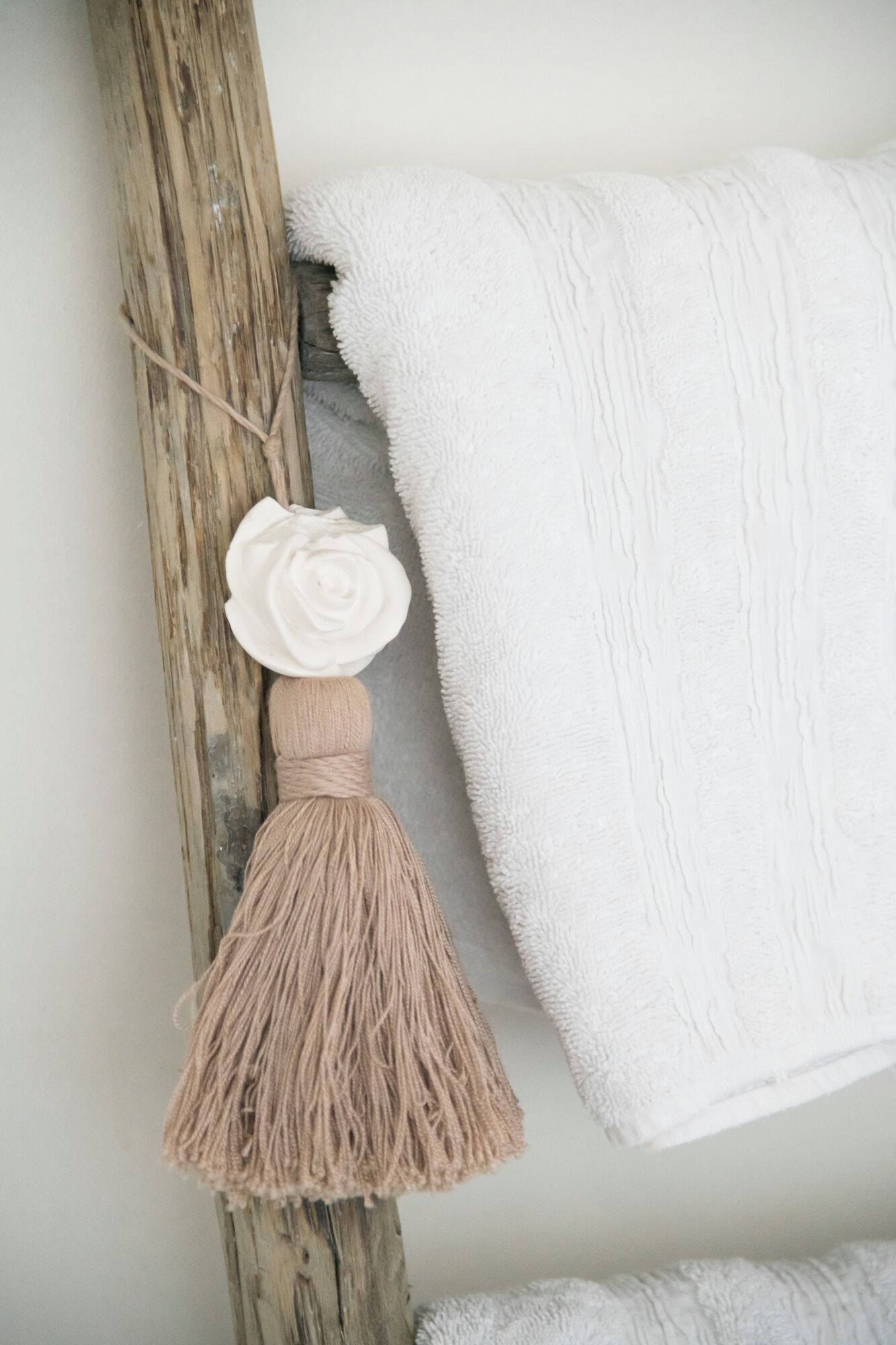 Una pared rústica con una toalla blanca y un colgador de macramé.