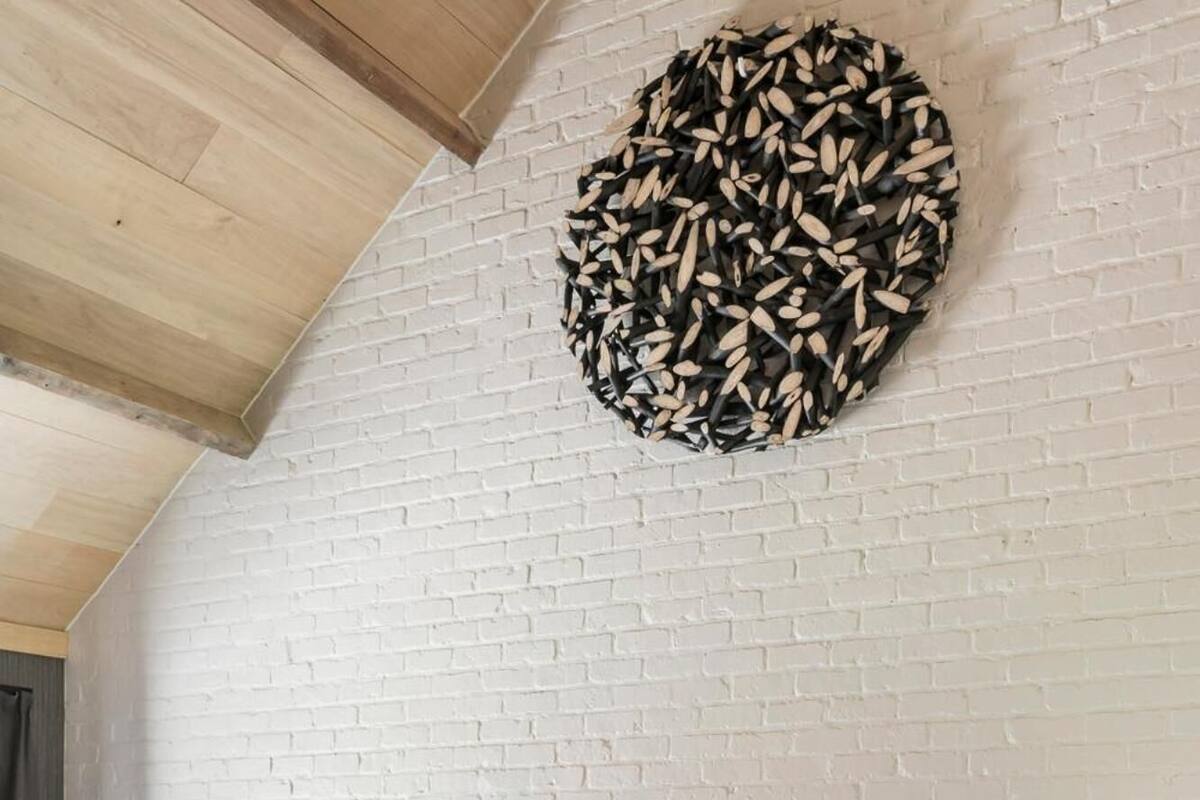 Quarto com cama, almofadas, uma cadeira e uma obra de arte na parede.