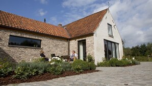 Une maison en briques avec un toit en tuiles, une grande fenêtre et une porte.