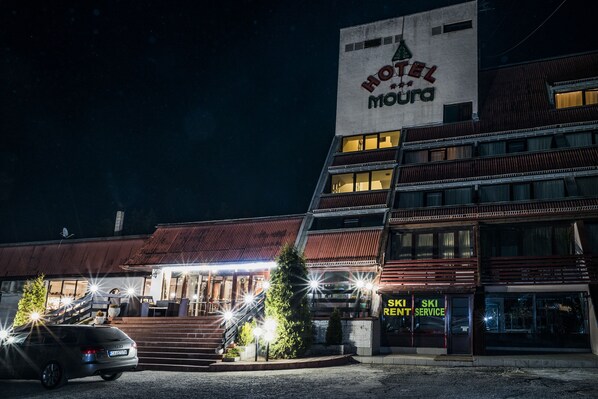 Un hotel con un letrero que dice "HOTEL MOUNTAI" y un servicio de alquiler de esquíes.