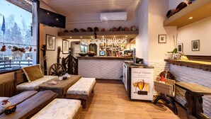 A cozy interior with a bar area, wooden furniture, and a view of snowy trees outside. - Hotel Moura (Samokov)
