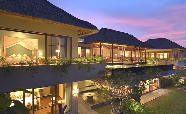 A multi-story resort with a thatched-roof structure, a pool, and lush greenery. - The Longhouse Jimbaran Bali (Jimbaran)