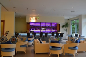 A bar area with a 'pico bar' sign, wicker furniture, and a large window.