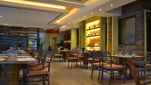 Ein Restaurant mit mehreren Tischen und Stühlen, einer Ziegelwand und einem modernen Deckenstil.