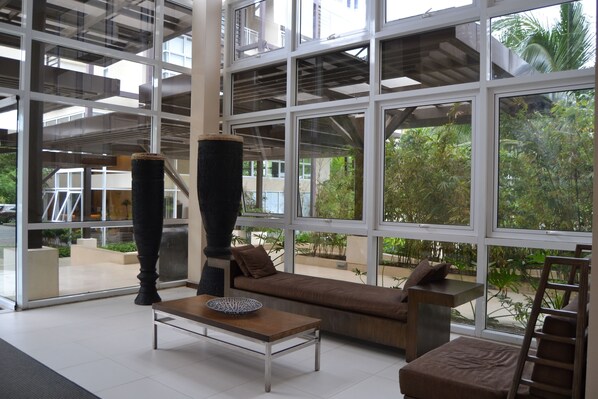 Un intérieur moderne avec de grandes fenêtres, un canapé, une table basse et un grand vase.