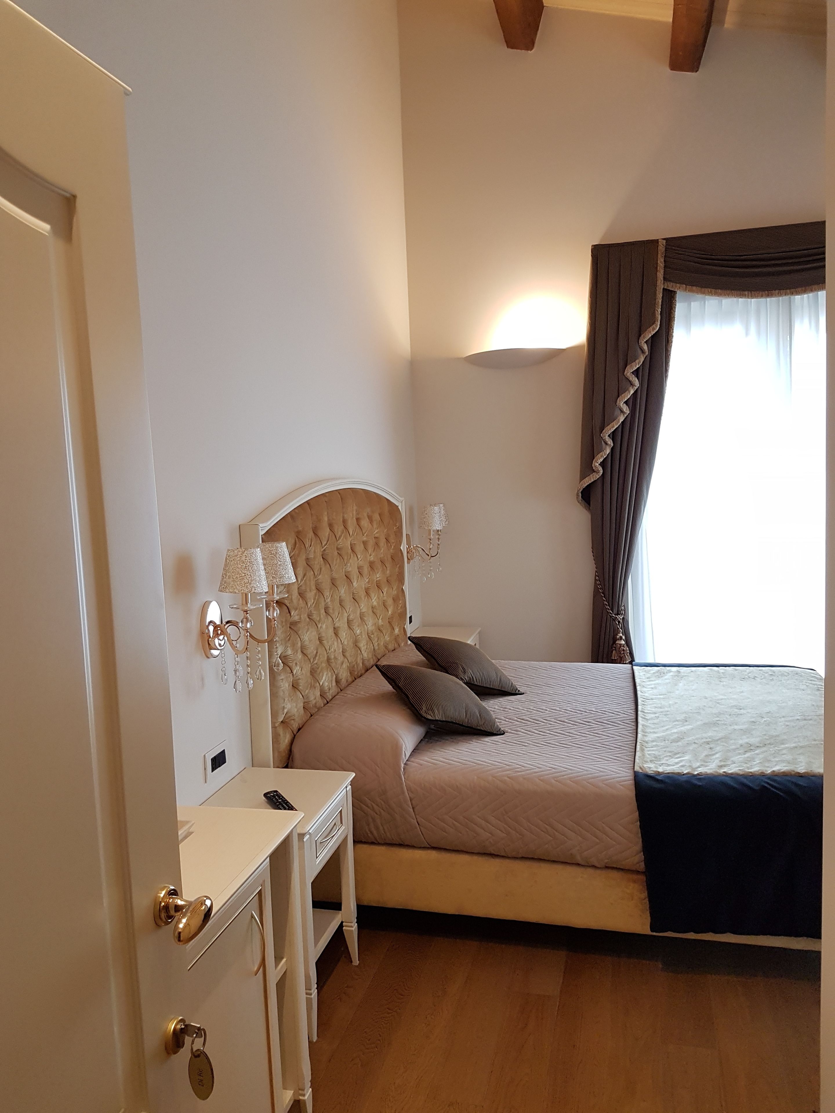 Un dormitorio con cama, mesita de noche, lámpara y vistas al exterior.