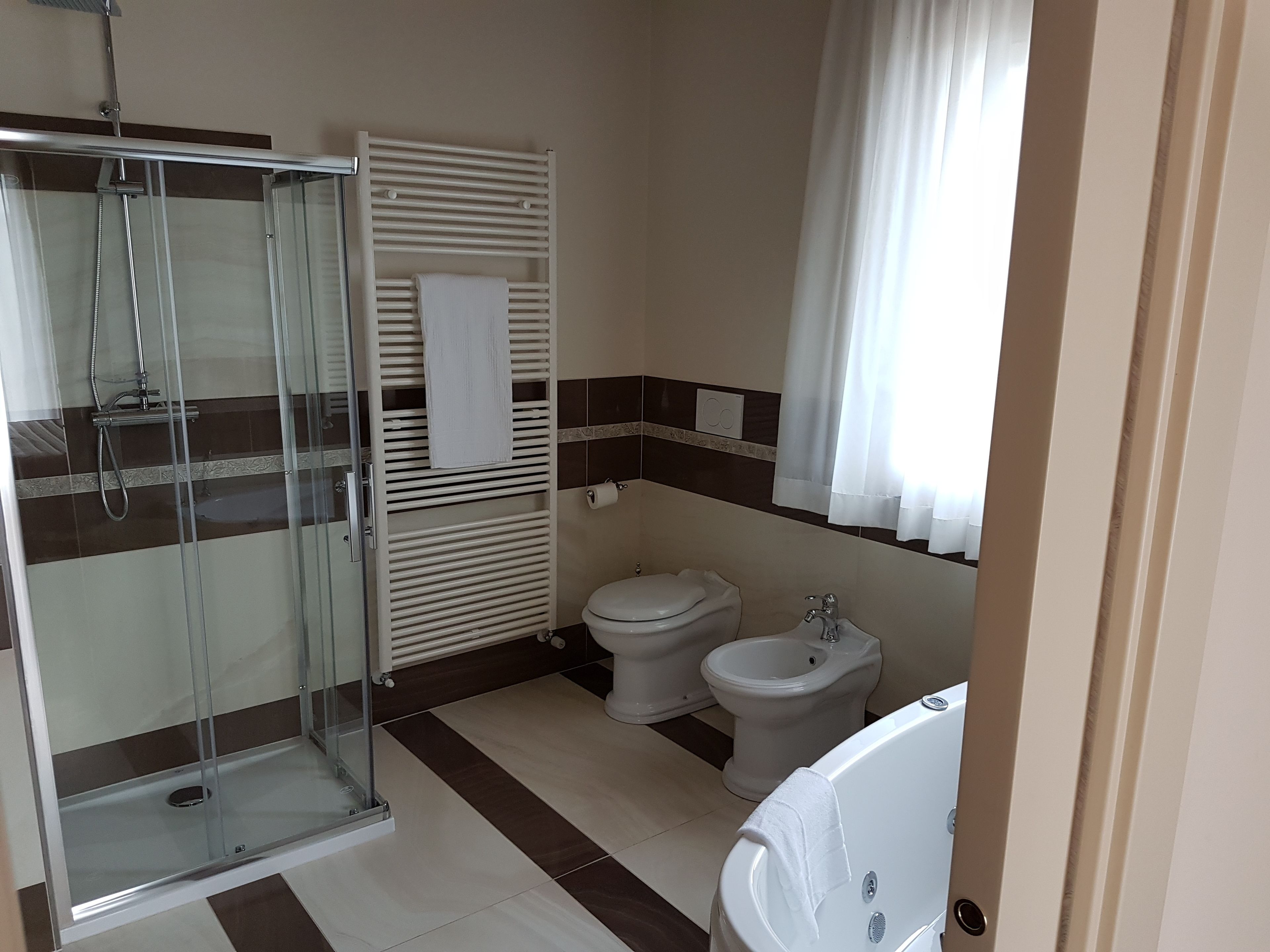 A bathroom with a glass-enclosed shower, a toilet, and a bathtub.