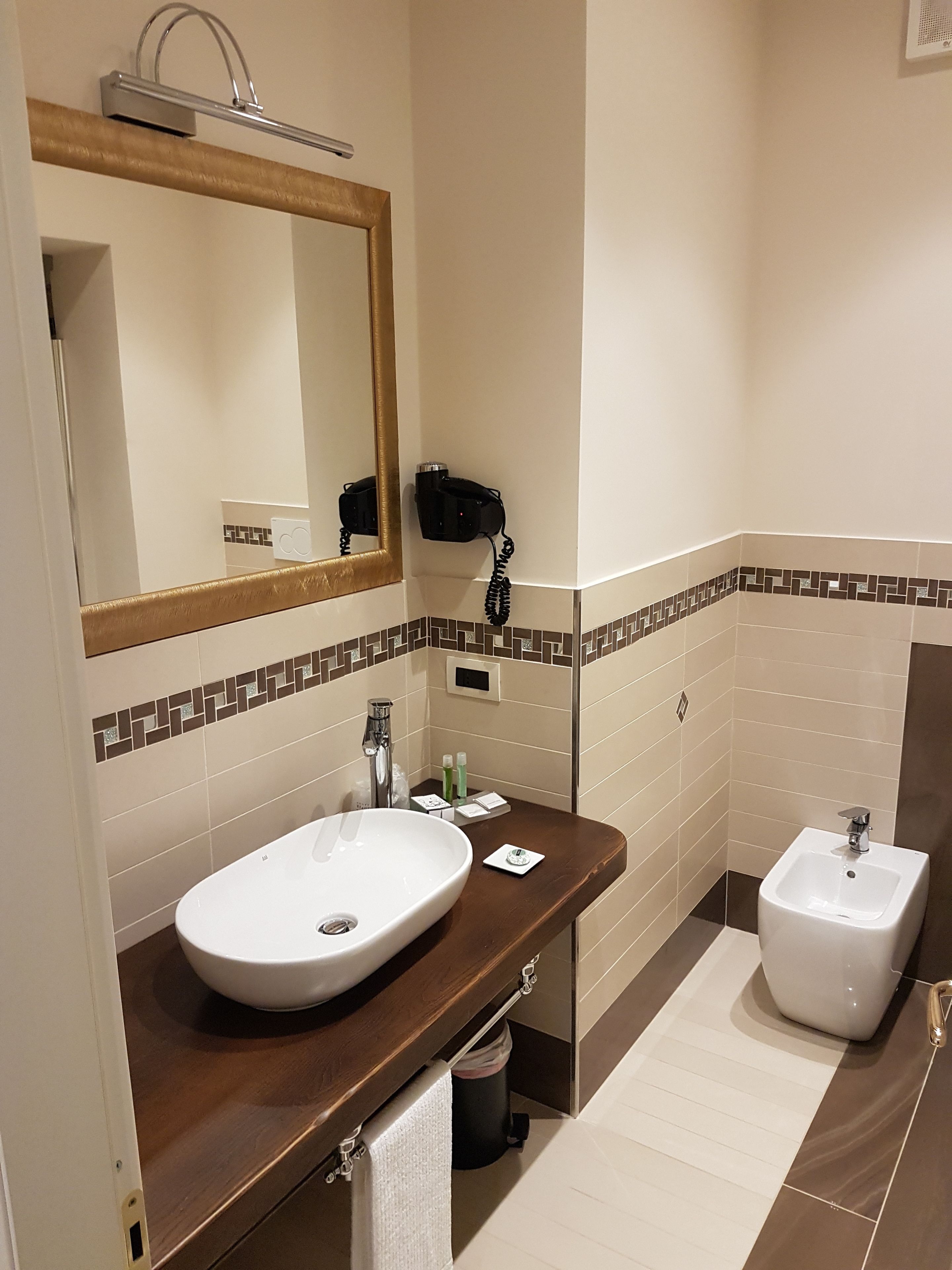 Un baño con un espejo grande, un lavabo, un bidé y un perchero para toallas.