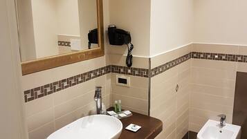 Un baño con un espejo grande, un lavabo, un bidé y un perchero para toallas.